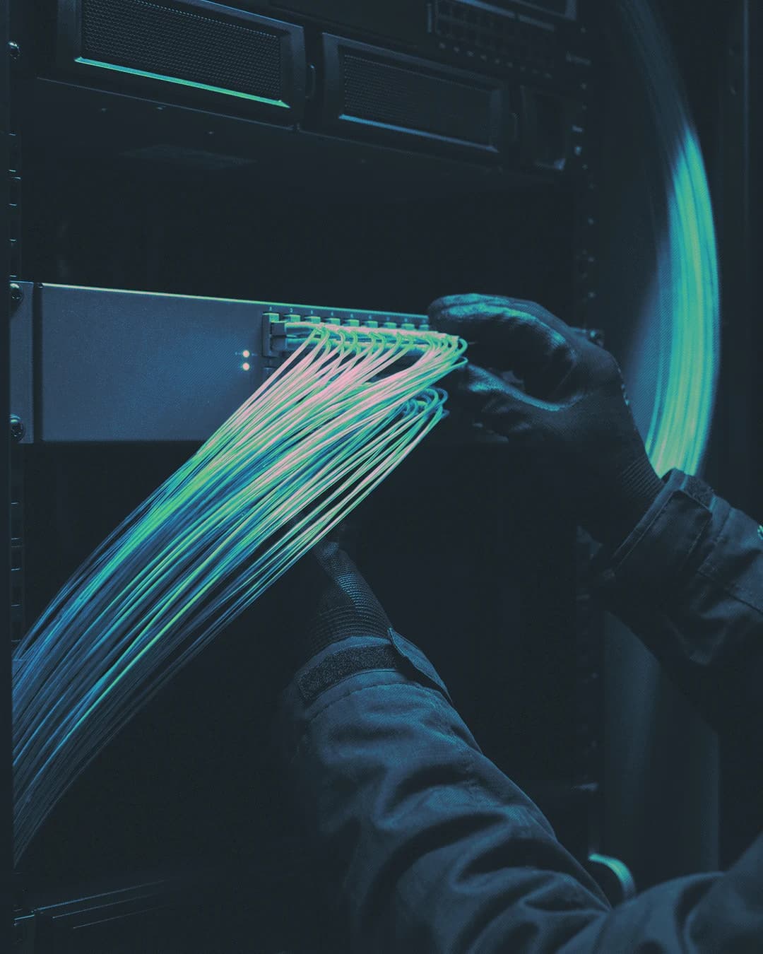 A person connecting cables to a server with blue and green motion trails.